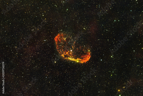 Принти на полотні An astrophotography image capturing the Crescent Nebula, NGC 6888, glowing with orange and red gas clouds surrounded by countless stars in the deep space background