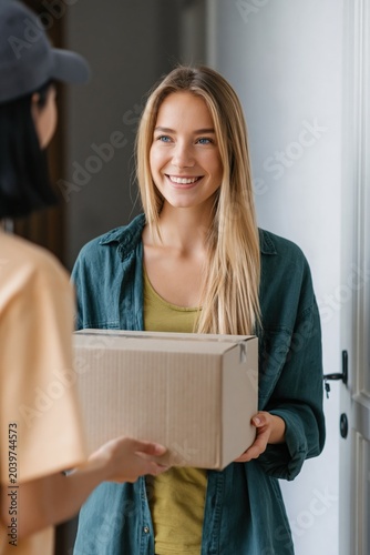 Young woman accepting package at apartment entrance