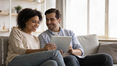 Smiling couple shares joyful moment while viewing content on tablet together at home