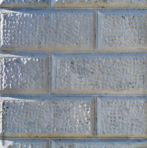 Wall made of facing decorative white stone. Close-up. Brick geometric textured background for design.