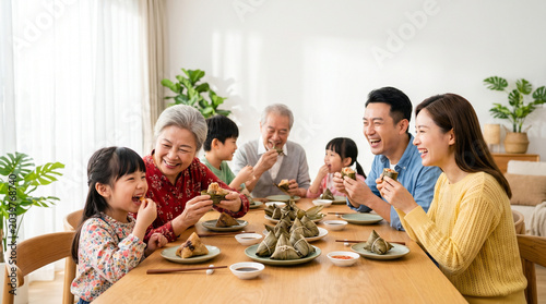 Family gathering enjoying zongzi at dining table during Dragon Boat Festival (Duanwu)