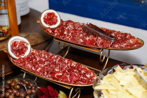 Artistic antipasto table with cured meats on golden stands and coconut shells