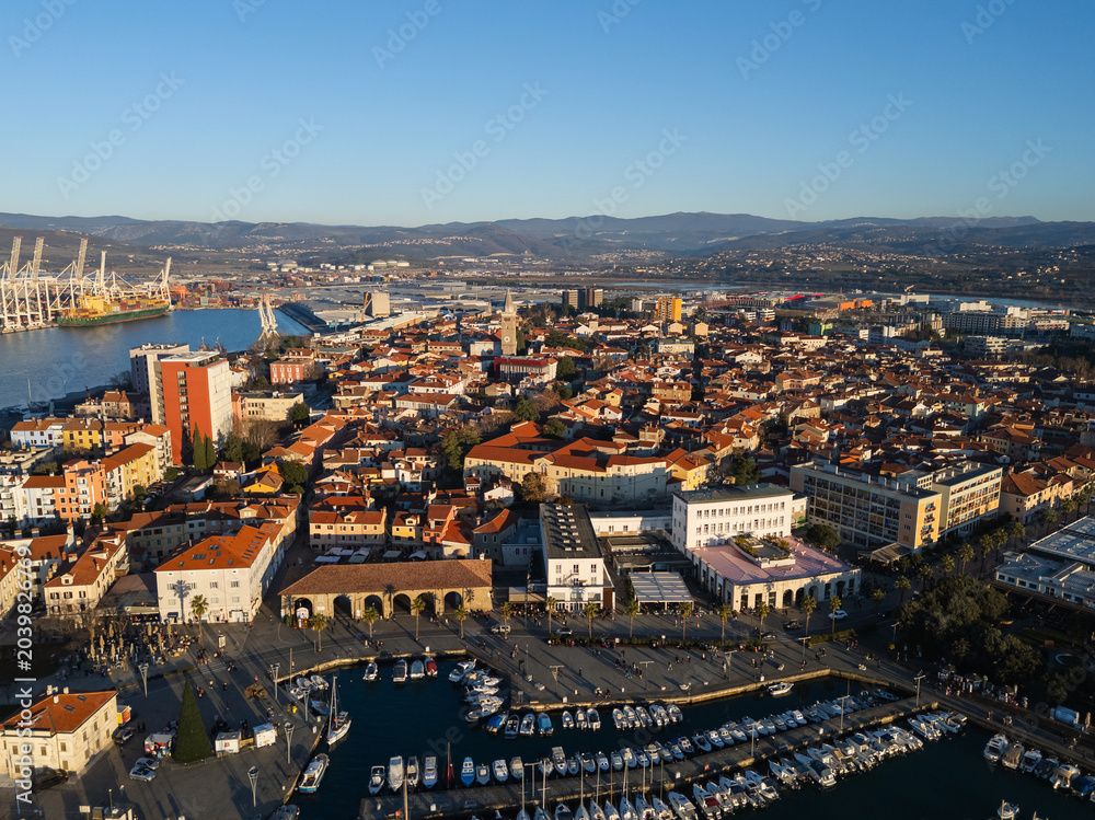 Obraz premium The view shows Koper, Slovenia with its marina, city buildings, and waterfront along the Adriatic Sea during daylight.