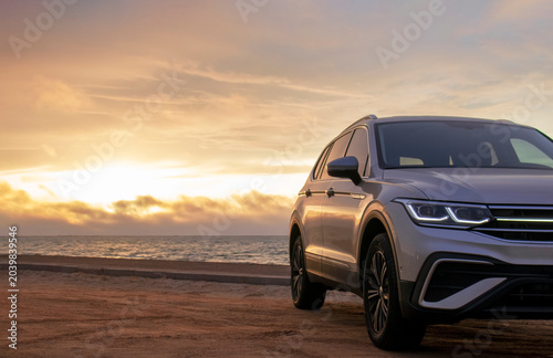 A gray SUV stands parked among the towering sand dunes of the Namib Desert under a dramatic cloudy sky. A bold visual of strength, solitude, and desert adventure.