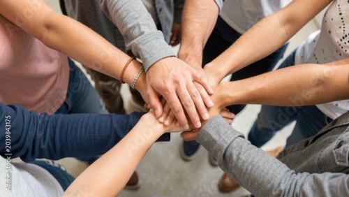 Close up top view of young people putting their hands together. Friends with stack of hands showing unity and teamwork.