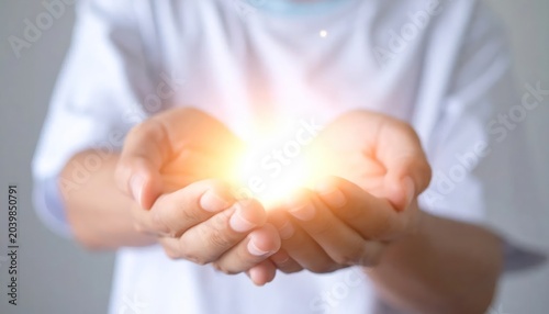 Close up of cupped hands holding brilliant golden light.