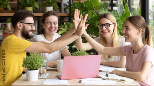 Group of Young Adults Celebrating High Five in Bright Green Indoor Space