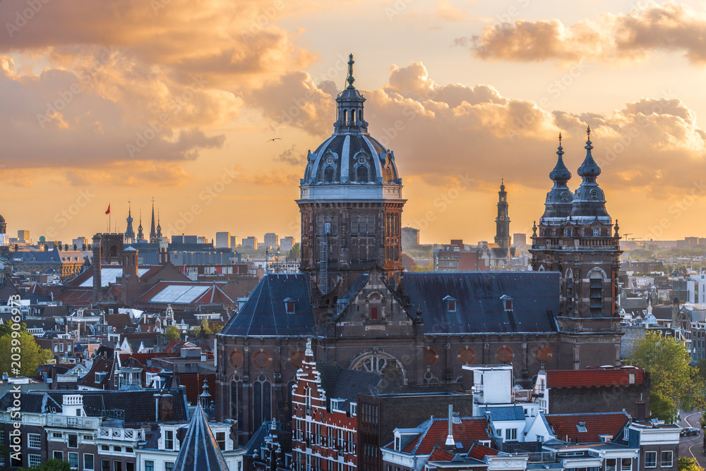 Obraz premium Amsterdam cityscape with St. Nicholas Basilica at sunset, aerial view of historic city center roofs, Netherlands