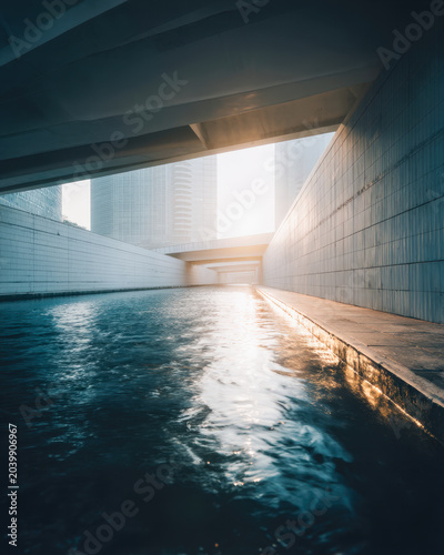 Stormwater Channel Under Modern Bridge with Sunlight Reflection