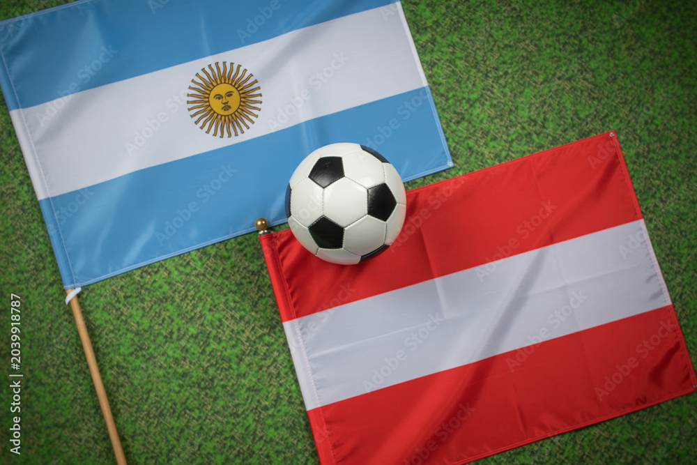 Fototapeta premium soccer ball between argentina and austria flags on grass photo football flag field sports competition international team spirit image realistic outdoor event