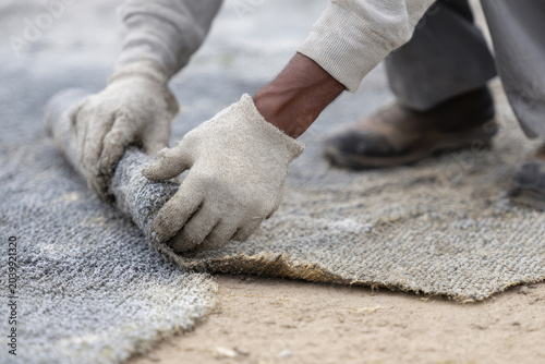 Worker glove hand rolling concrete curing blanket construction site outdoor worker wearing gloves rolls up concrete curing blanket construction site focusing hands and texture showing careful