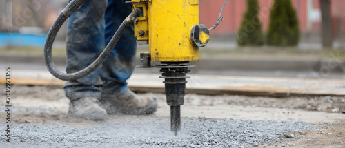 Worker concrete jackhammer construction tool heavy equipment breaking road dust outdoor industrial manual labor safety work machinery power site repair worker operating heavy concrete jackhammer