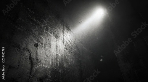 Bright beam of light illuminating a dark cave wall in black and white.