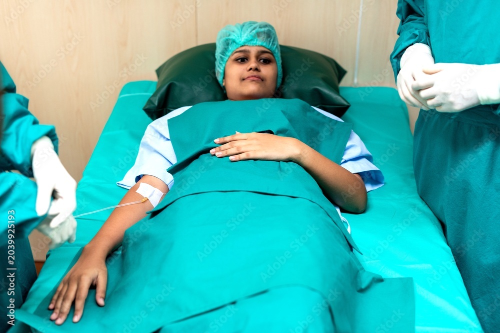 Obraz premium Female South Asian patient recovering in hospital bed with medical staff