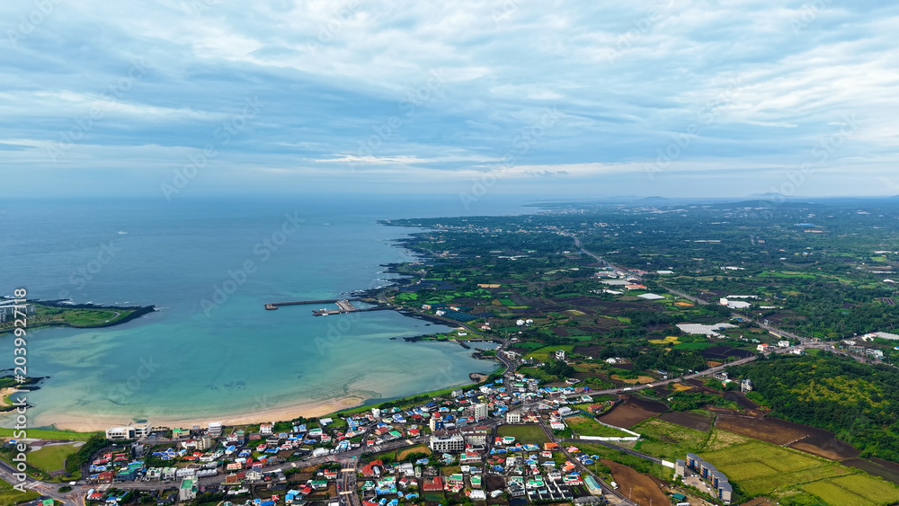 Fototapeta premium Aerial drone view of Seongsan Ilchulbong coastal village farmland and ocean landscape in Jeju Island South Korea
