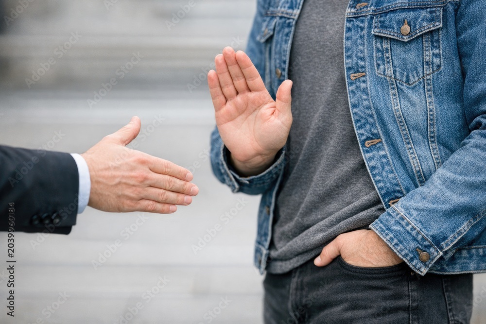Fototapeta premium Two men in different attire shake hands, symbolizing a deal or agreement