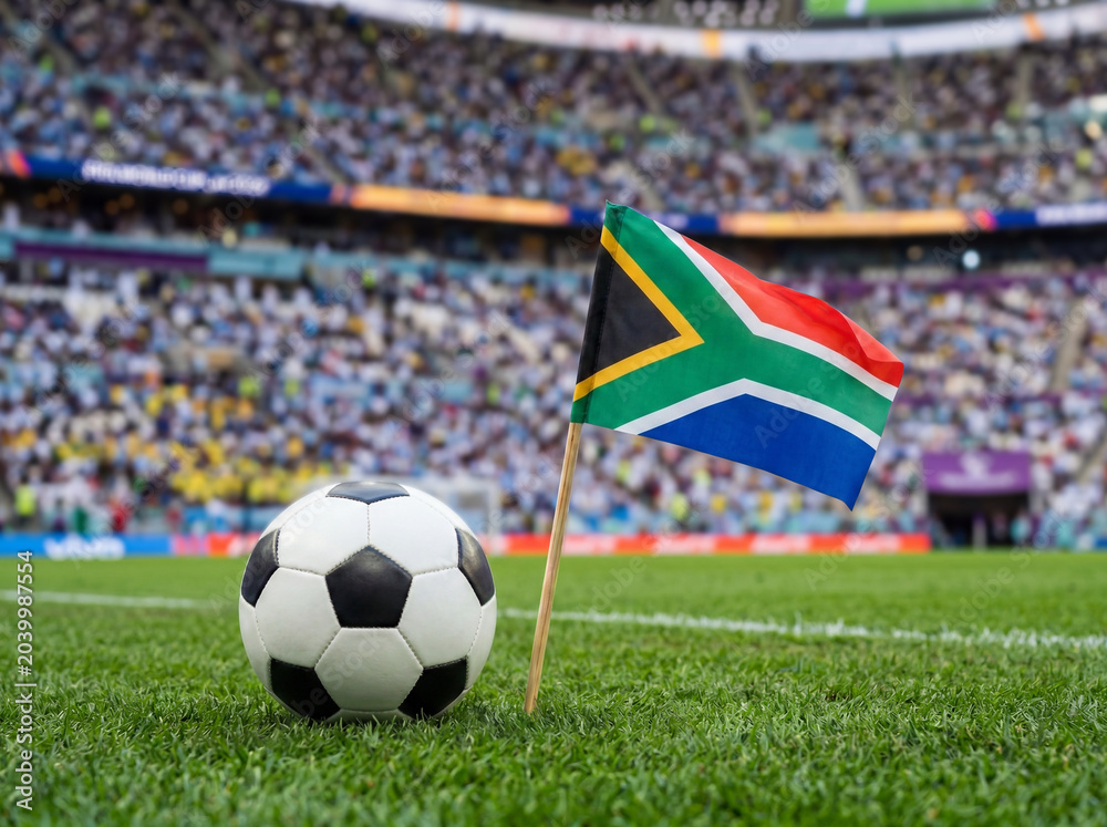 Naklejka premium South african flag and football on green field in stadium