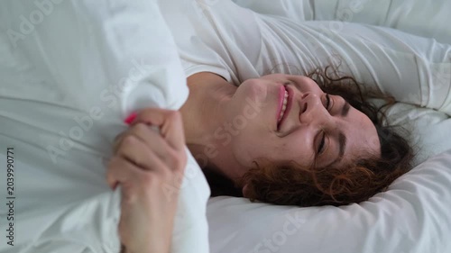 Young woman sleeping in bed. Portrait of a beautiful woman resting on a comfortable bed with pillows in white bedding in the bedroom in the morning. High quality image.