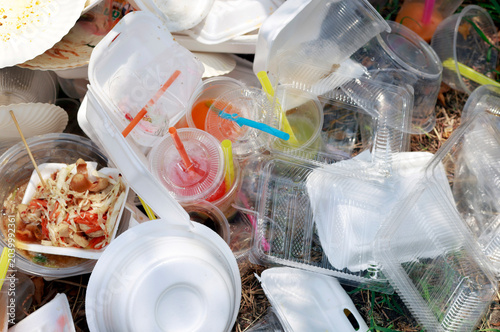 Pile of used plastic containers, cups, plastic waste, takeaway food packaging outdoors, highlighting single-use waste, environmental pollution, consumer habits, and recycling challenges