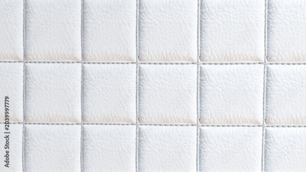 Fototapeta premium The surface texture of white faux leather, stitched in diamond, square, and rectangular patterns. Quilted eco-leather