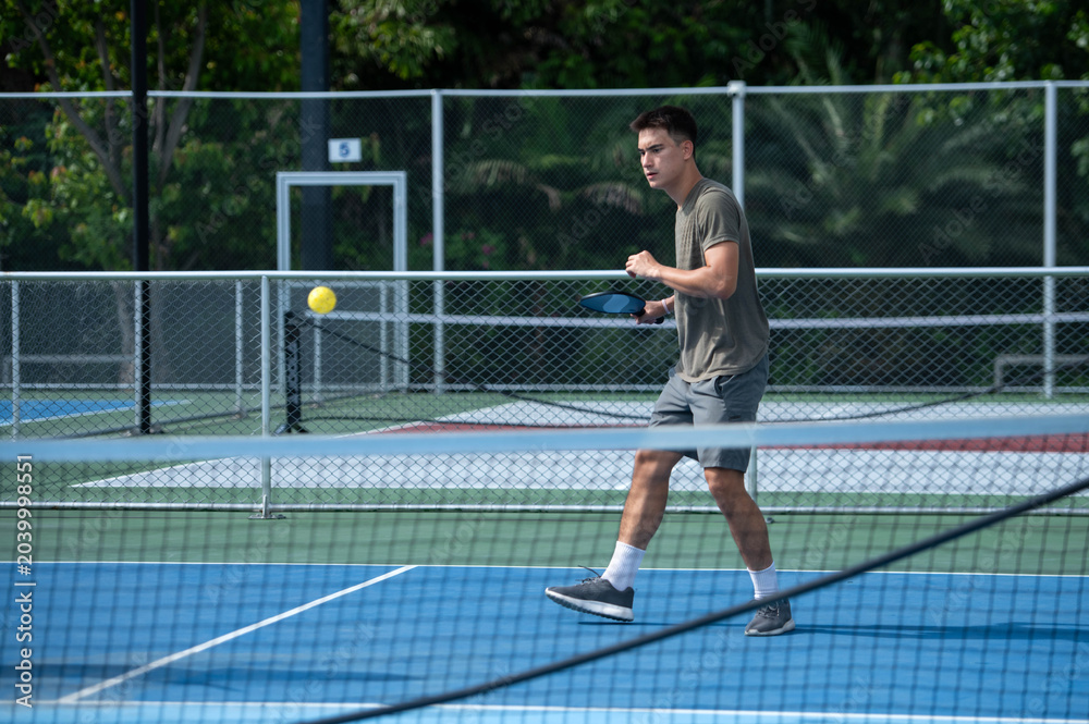 Obraz premium Young male athletes playing pickleball and practicing for competition on an outdoor field