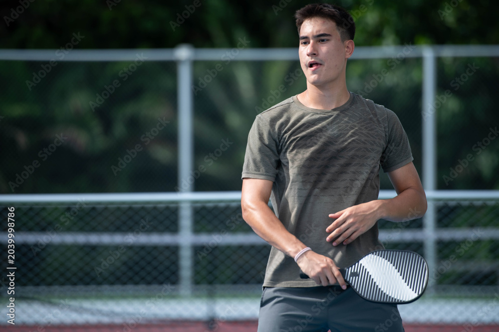 Naklejka premium Young male athletes playing pickleball and practicing for competition on an outdoor field