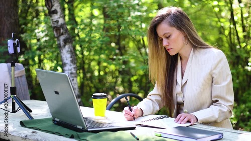 Slow motion 4k footage of a writer during work in front of a laptop monitor in a city park. Freedom from the confines of a stuffy office in a noisy city.
