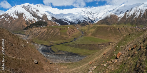 snow-capped mountain peaks, green slopes and river valley