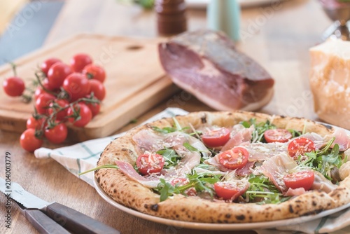 Bild auf Leinwand A beautifully crafted pizza is presented with vibrant cherry tomatoes and pepper