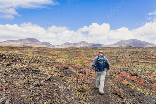 A hiker exploring the rugged, otherworldly volcanic landscape of Lanzarote, Canary Islands. Lanzarote offers active outdoor tourism and opportunities for nature exploration.