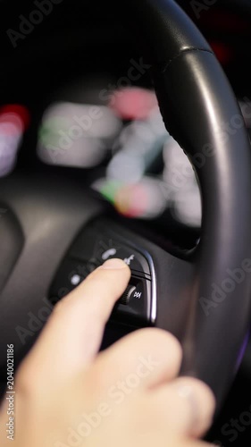 Vertical view of steering wheel of car control music. The hand turns the volume of the radio in the car. Close up of radio volume. Music in the car. Modern music technology
