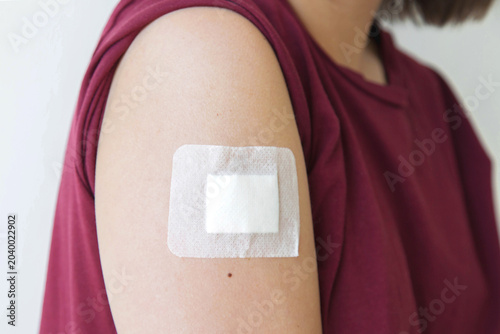 Medical adhesive bandage on upper arm, closeup of woman shoulder with sterile dressing after minor medical procedure, injection or mole removal, healthcare, recovery, wound care, dermatology, 