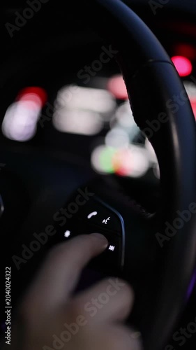Vertical format video of steering wheel of car control music. The hand turns the volume of the radio in the car. Close up of radio volume. Music in the car. Modern music technology