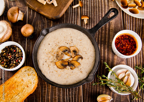 Foto Creamy mushroom soup in a cast iron skillet, garnished with herbs and spices