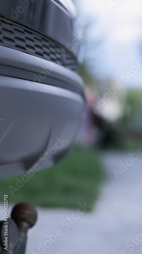 Vertical video of Tow bar and tow ball on a car. Towbar on car black steel part. Car detail. Foldable tow device switch. Extending and retractable towbar. Deployable Electric Tow Bar