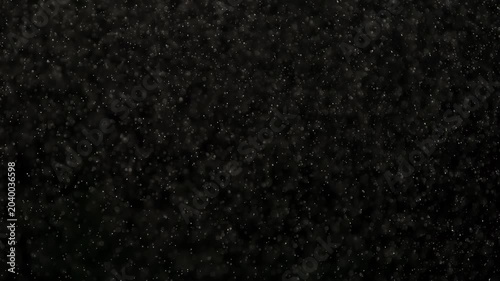 White Microparticles in Flight. Small white particles flow in the air on a black background. Slow Motion