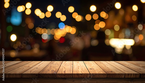 Wooden table surface in front of a blurred bokeh background of warm, glowing string lights at night, creating a cozy ambiance