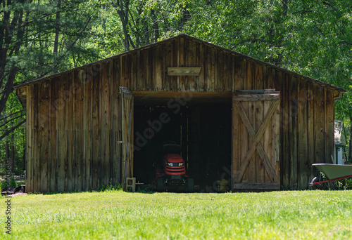 Lawn mower in old wooden shed, grass cutting, background image, landscaping season, copy space image