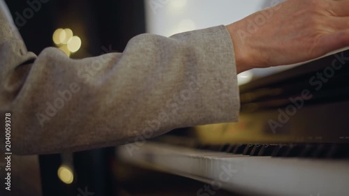 Hands play piano. Secluded practice with warm lights. Focused musician practicing alone amid cozy indoor ambiance. Closeup of fingers on keys with gentle lighting and sheet music nearby