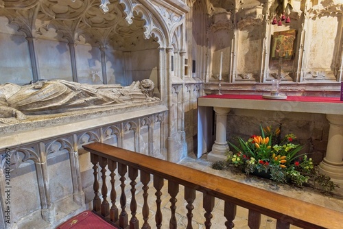 Fotografie An ornate stone effigy lies on a tomb within a historic chapel, featuring Gothic