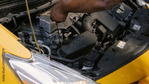 Bild auf Leinwand Close-up mechanic hands repairing engine inside yellow hybrid taxi hood compartm