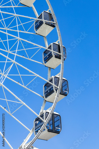 Ferris wheel cabins and geometric framework against vibrant blue sky background
