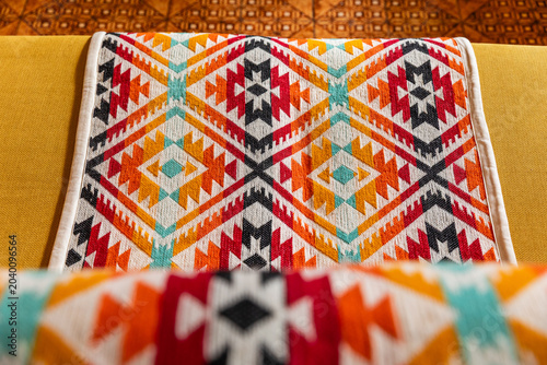Canvas Print Yellow sofa decorated with colorful indigenous handmade blanket in a cozy living room interior