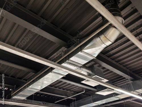 Ventilation and piping network mounted on factory ceiling supporting efficient air circulation across industrial facility