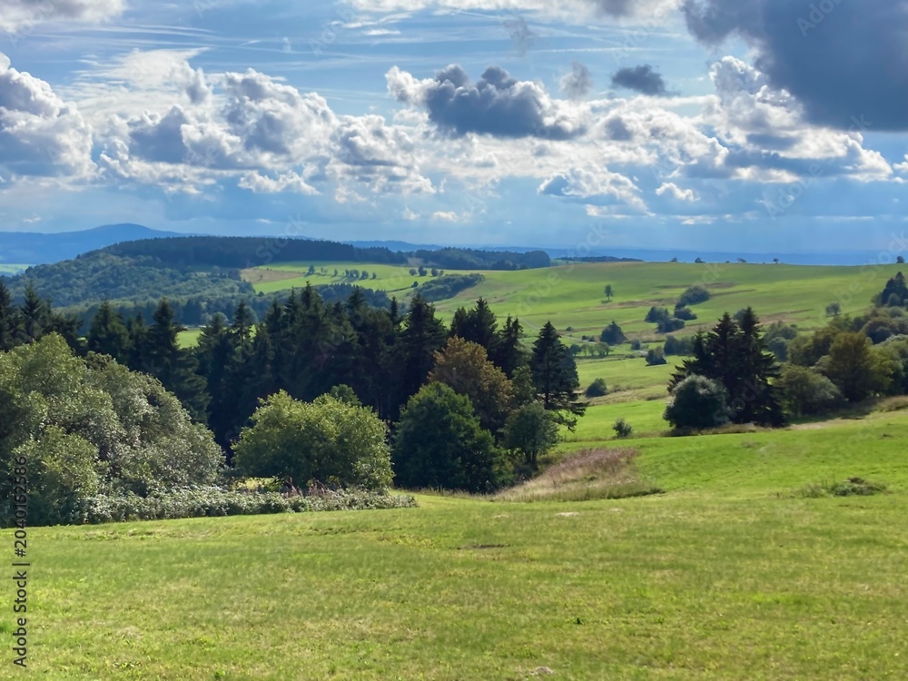 Obraz premium panorama of beautiful countryside of Rhoen, Hesse, Germany. sunny afternoon. wonderful springtime landscape in mountains. grassy field and rolling hills. rural scenery.