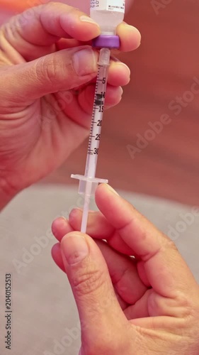 Person preparing an insulin syringe for injection