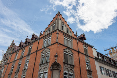 Low angle view of a historic red brick building with neo-gothic architectural details and a decorative stepped gable