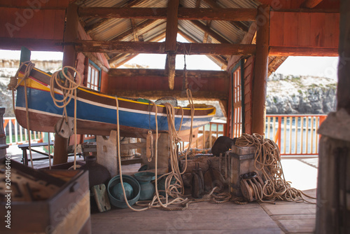 Fotografi Traditional Maltese fishing boat Luzzu in a rustic wooden boathouse