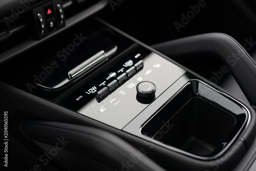 Close-up of a luxury car center console climate control panel with tactile switches