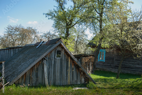 Old wooden village barns with a stack of firewood in the yard.